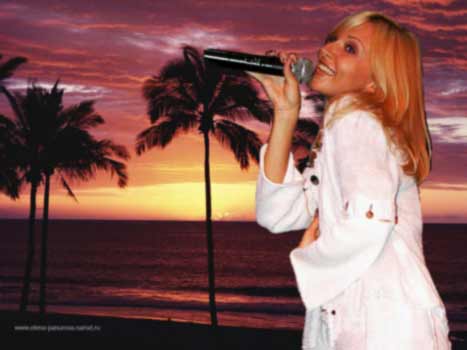На фотографии изображена Елена Панурова в белом платье с микрофоном в руке, на фоне восхода солнца в тропическом лесу на берегу моря.
